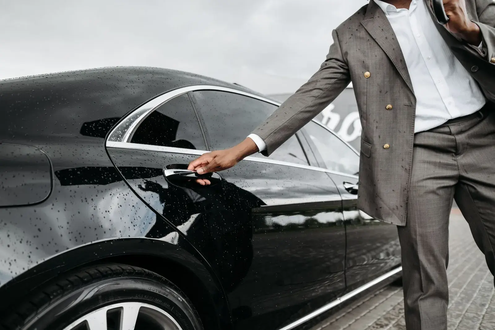 A chauffeur opening a black car door