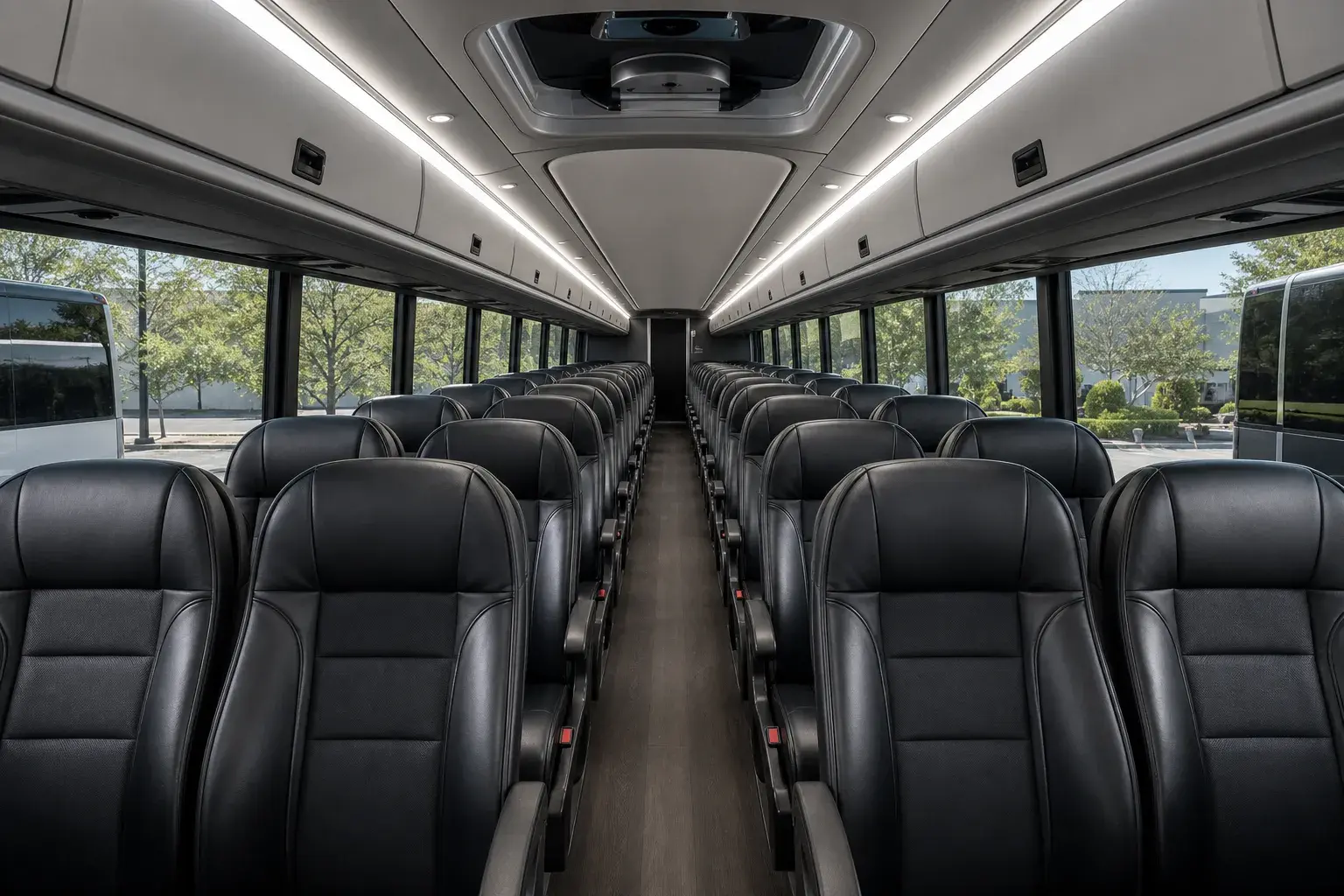 full-size luxury motor coach passenger cabin — black leather seating, bright neutral interior