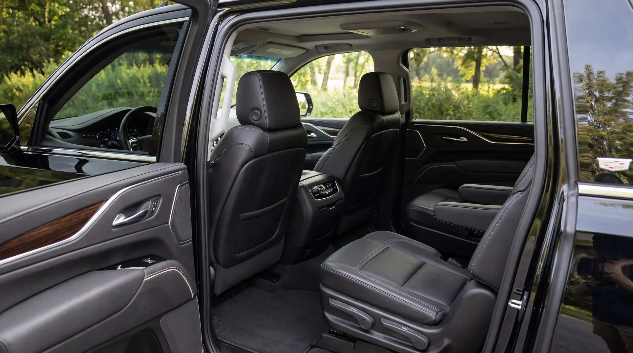 Cadillac Escalade ESV second-row cabin — black leather captain's chairs, soft daylit view through the windows