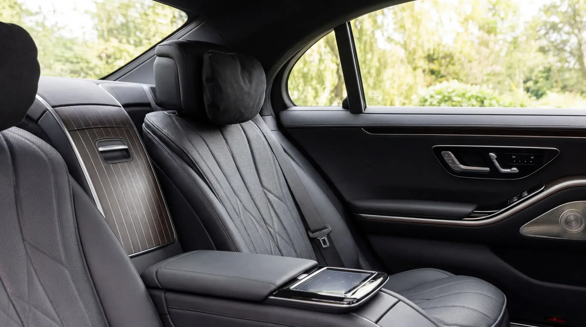 Mercedes-Benz S-Class rear seat detail — quilted black leather with headrest pillow, soft daylit view through the windows