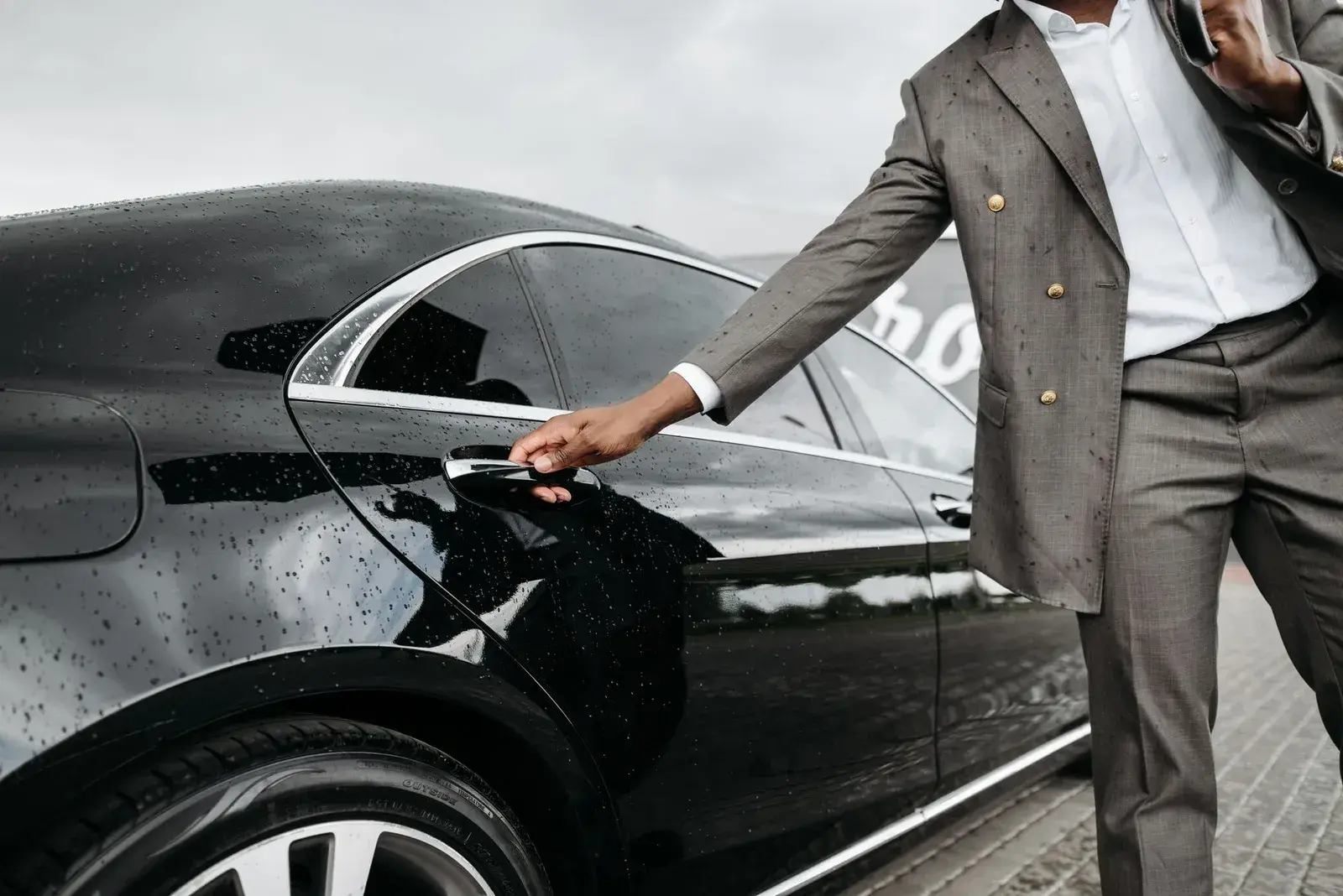 A chauffeur opening a black car door