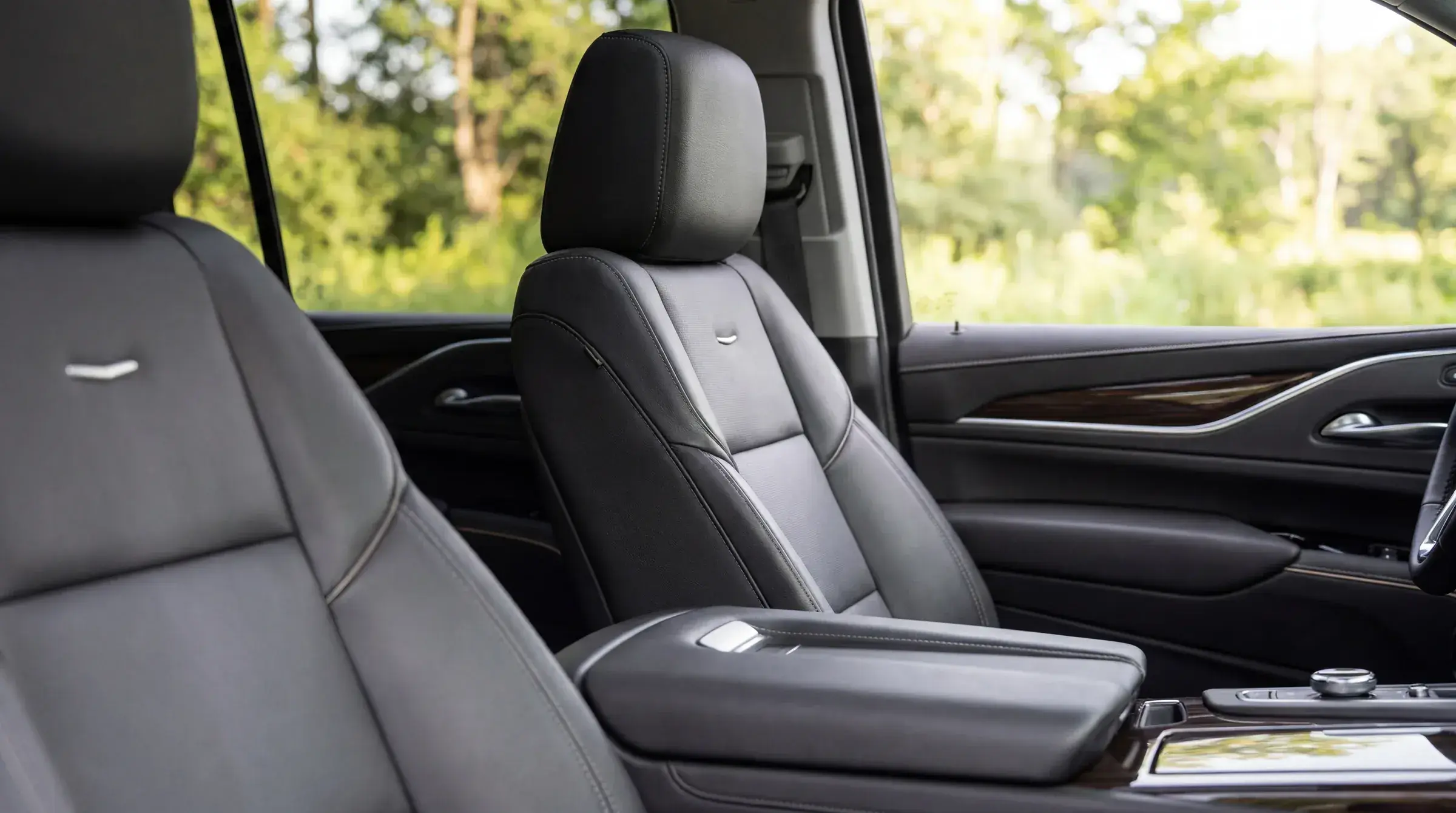 Cadillac Escalade ESV second-row seat detail — black leather captain's chair, soft daylit view through the windows