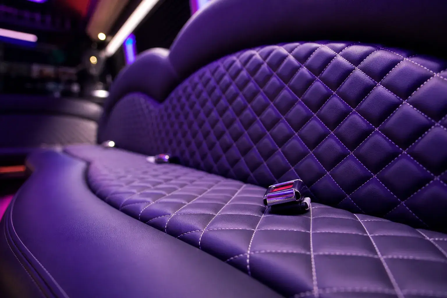 Limo Sprinter seat detail — purple quilted diamond-stitched leather lounge seating with white contrast stitching and chrome seatbelt buckle